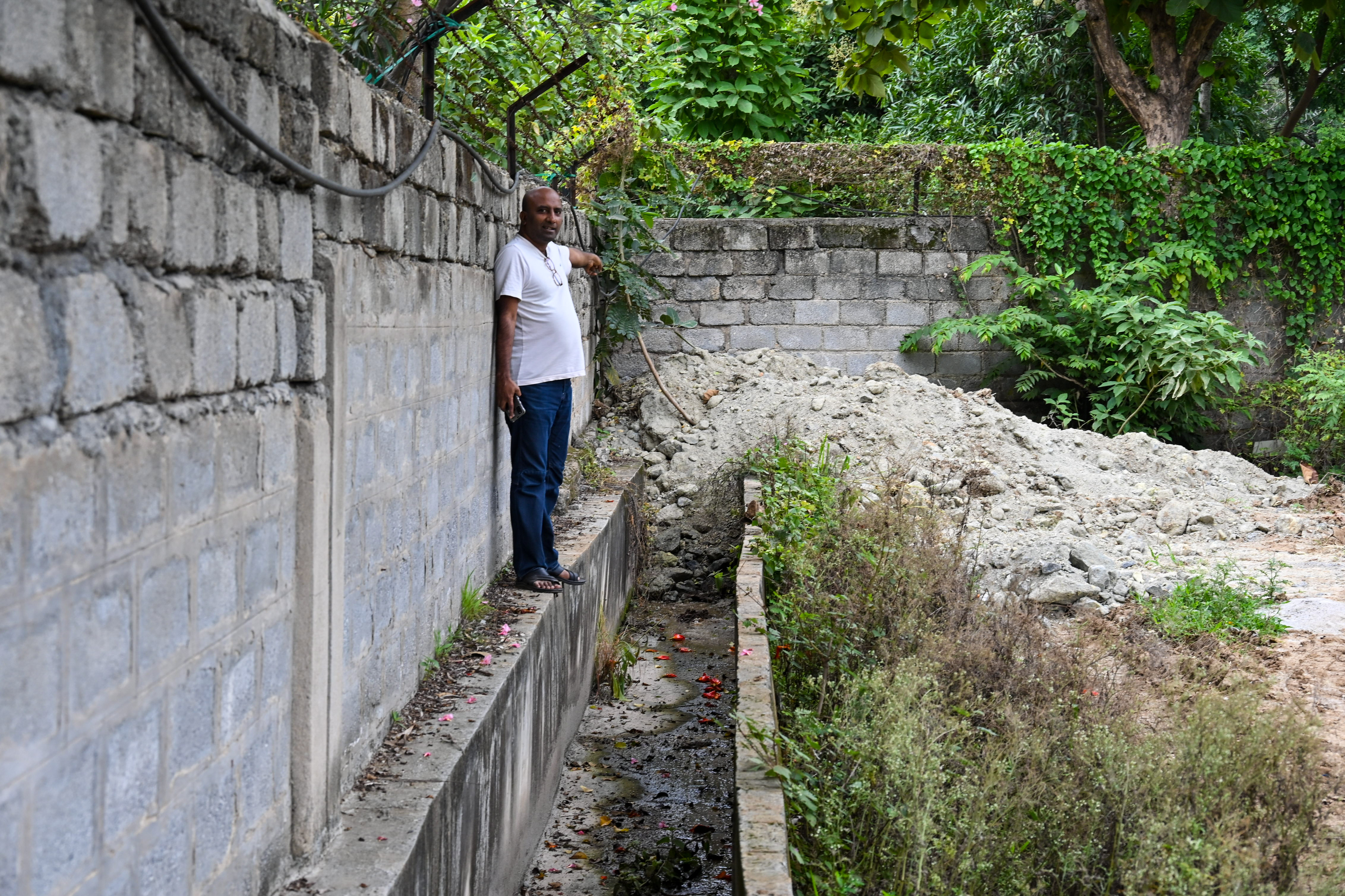An activist points to a blocked stormwater drain near the lake. 