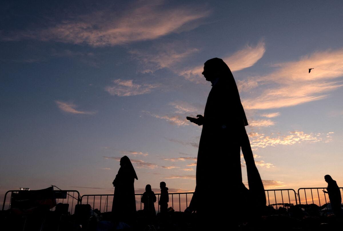 A pilgrim walks at dawn after spending the night at Tor Vergata where Pope Leo will lead a mass for the Jubilee of Youth in Tor Vergata, Rome, Italy, August 3, 2025.