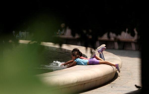 Children cool off at the Smithsonian Sculpture Garden’s fountain in Washington, DC, US.
