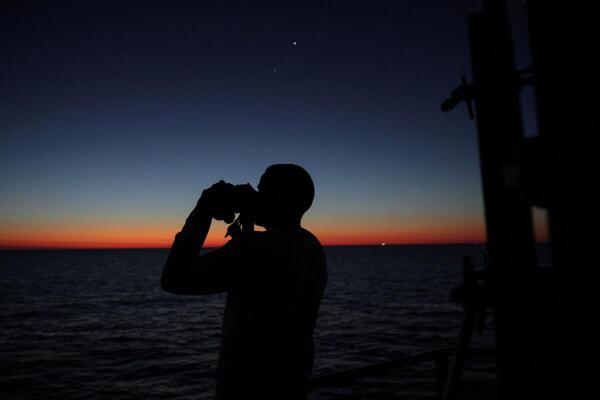 A crew member of the migrant search and rescue ship Sea-Watch 5, operated by the German NGO Sea-Watch, looks through binoculars before sunrise, as the ship operates in the search and rescue (SAR) zone in the central Mediterranean Sea, off Libya.