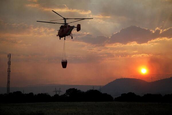 A firefighting helicopter flies over Rogami suburb during sunset, as temperature rises during a heatwave in Podgorica, Montenegro.