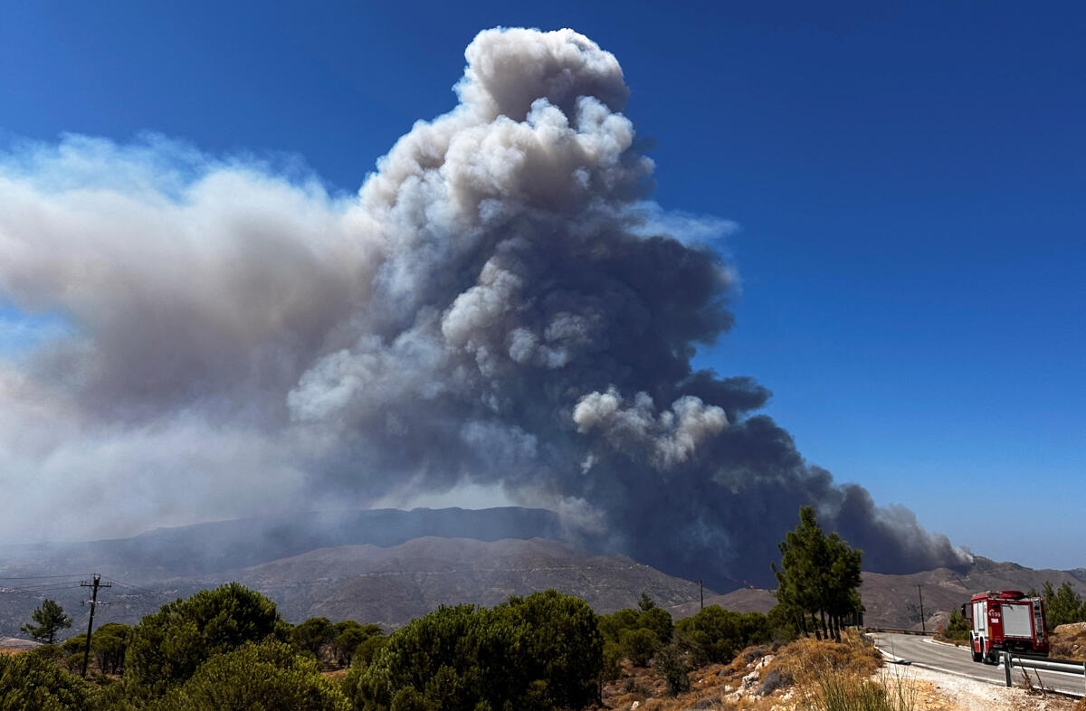 A firefighting vehicle drives towards a wildfire burning on the island of Chios, Greece