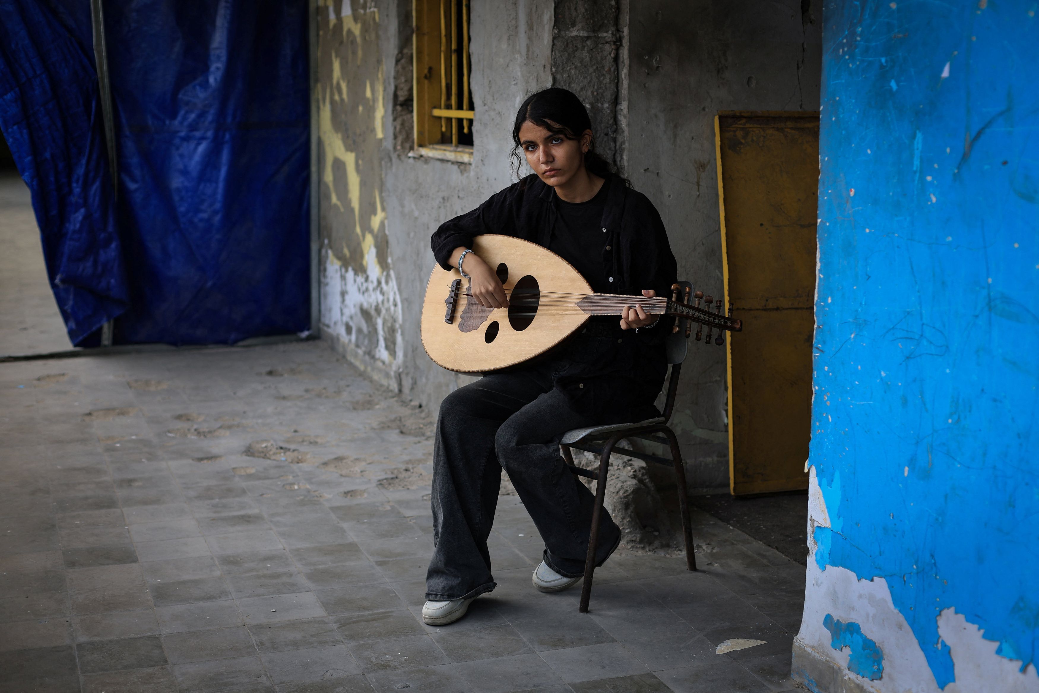 Palestinian Rifan Al-Qassas, 15, holds an oud as she poses for a portrait at Gaza College, where instructors from Edward Said National Conservatory of Music train Palestinians, in Gaza City, August 9, 2025. 