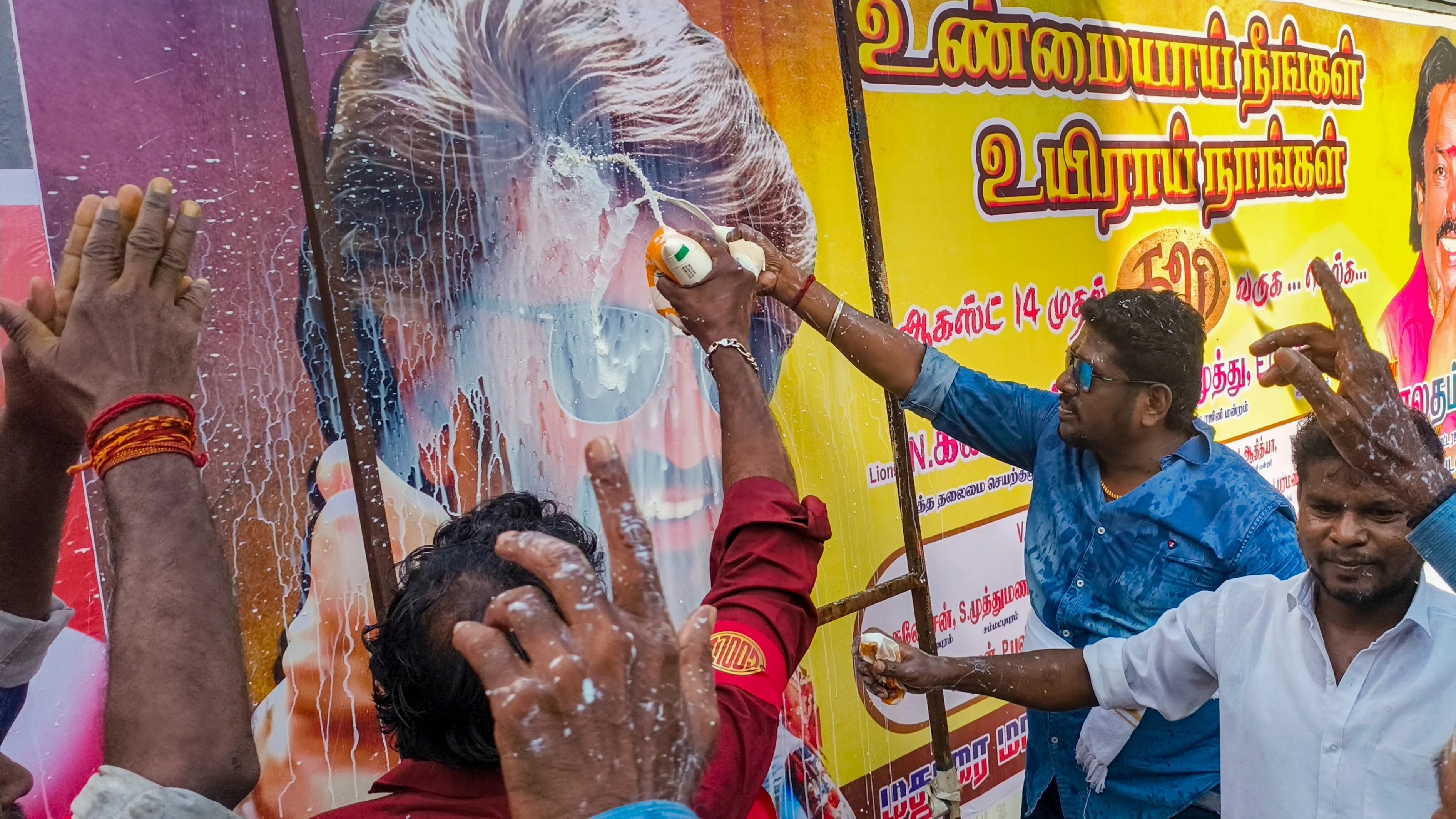 Fans of superstar Rajinikanth pour milk on the posters as they celebrate the release of Coolie in Madurai.
