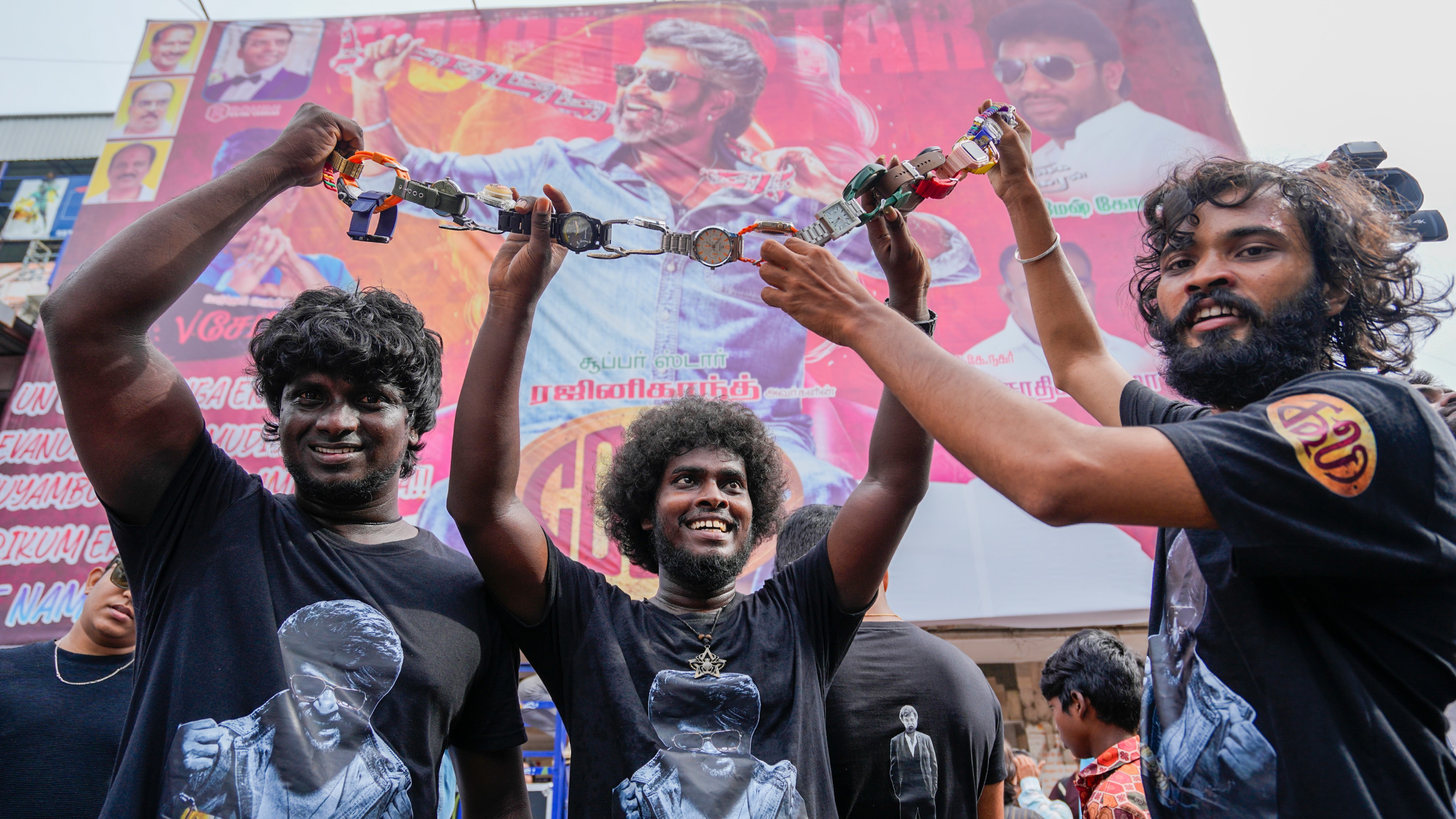 Fans of superstar Rajinikanth show a chain of wristwatches, depicting a sequence from Coolie, during celebrations outside a movie theater in Chennai.
