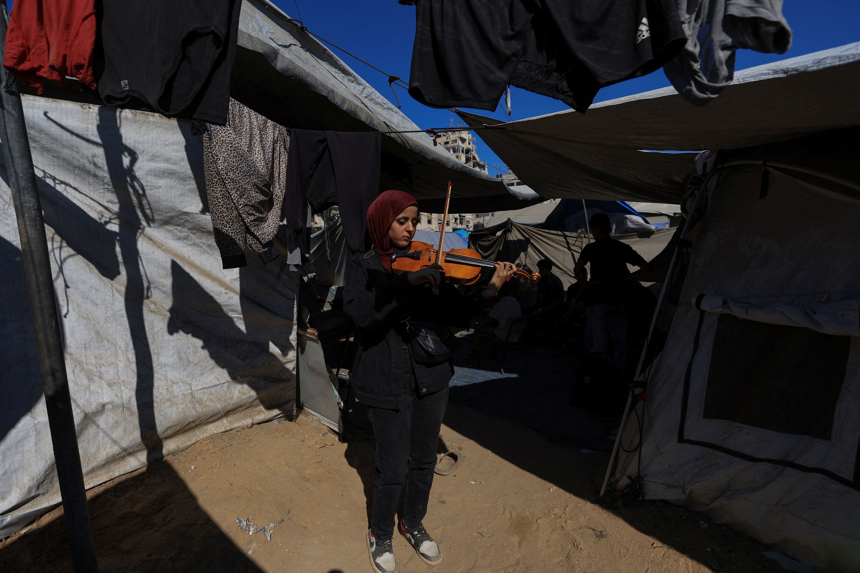 Palestinian musician Sama Najam, of the Edward Said National Conservatory of Music, plays a a string musical instrument inside a tent in Gaza City, August 4, 2025. 