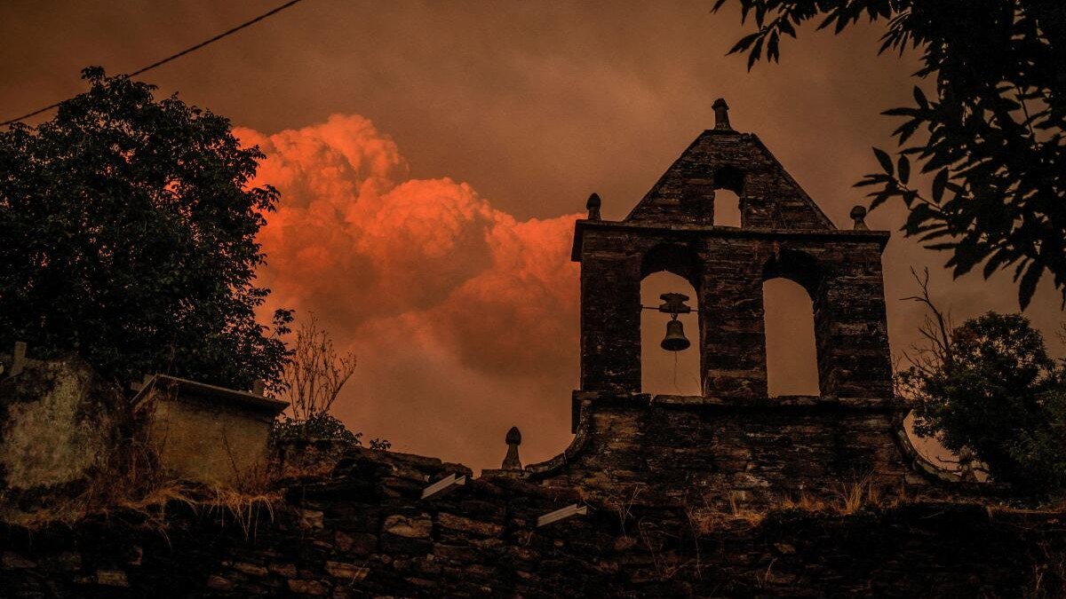 A pyrocumulus cloud forms as smoke rises from a wildfire as seen from a cemetery in the village of Vilarmel, Lugo area, Galicia region, Spain.