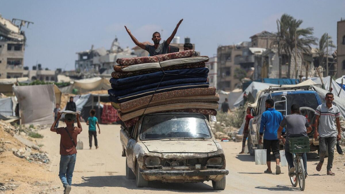 A displaced Palestinian man fleeing northern Gaza gestures atop a vehicle loaded with belongings while he heads south as the Israeli military prepares to relocate residents to the southern part of the enclave, in Gaza City.
