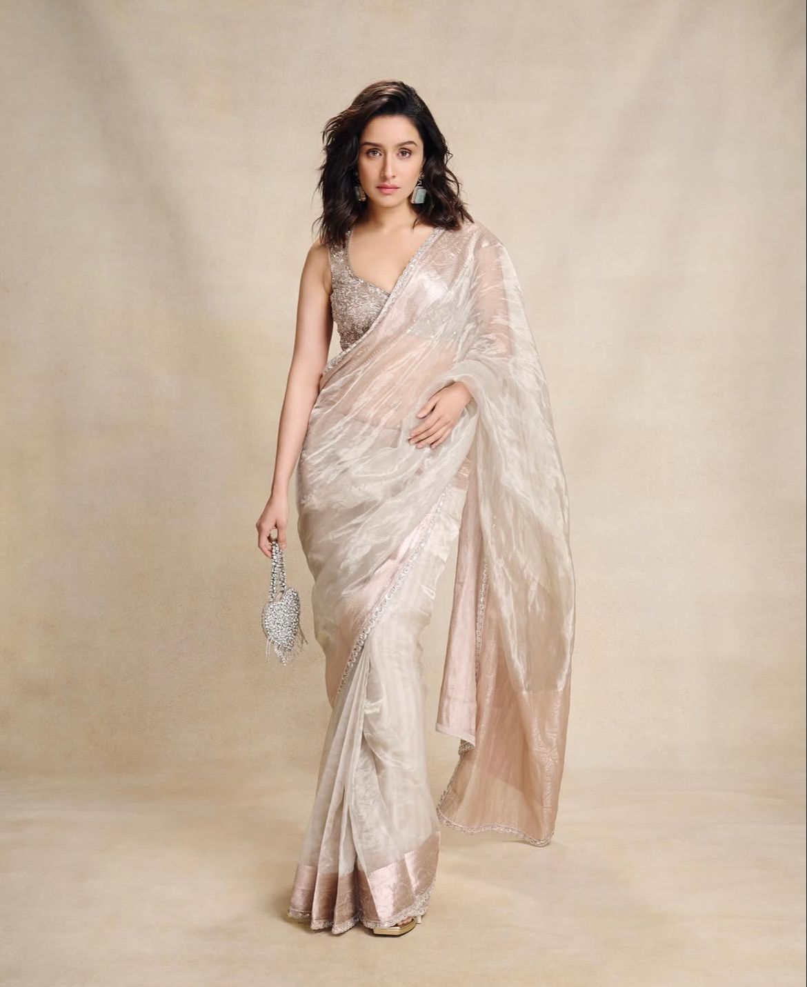 Shraddha Kapoor
shows how to add sparkle! The actress dazzles in a silver tissue saree and pairs it with a fully embellished blouse. Keeping it simple and effortless she accessorises her look with stone jewellery and gets the game going on with a heart-shaped mini bag.