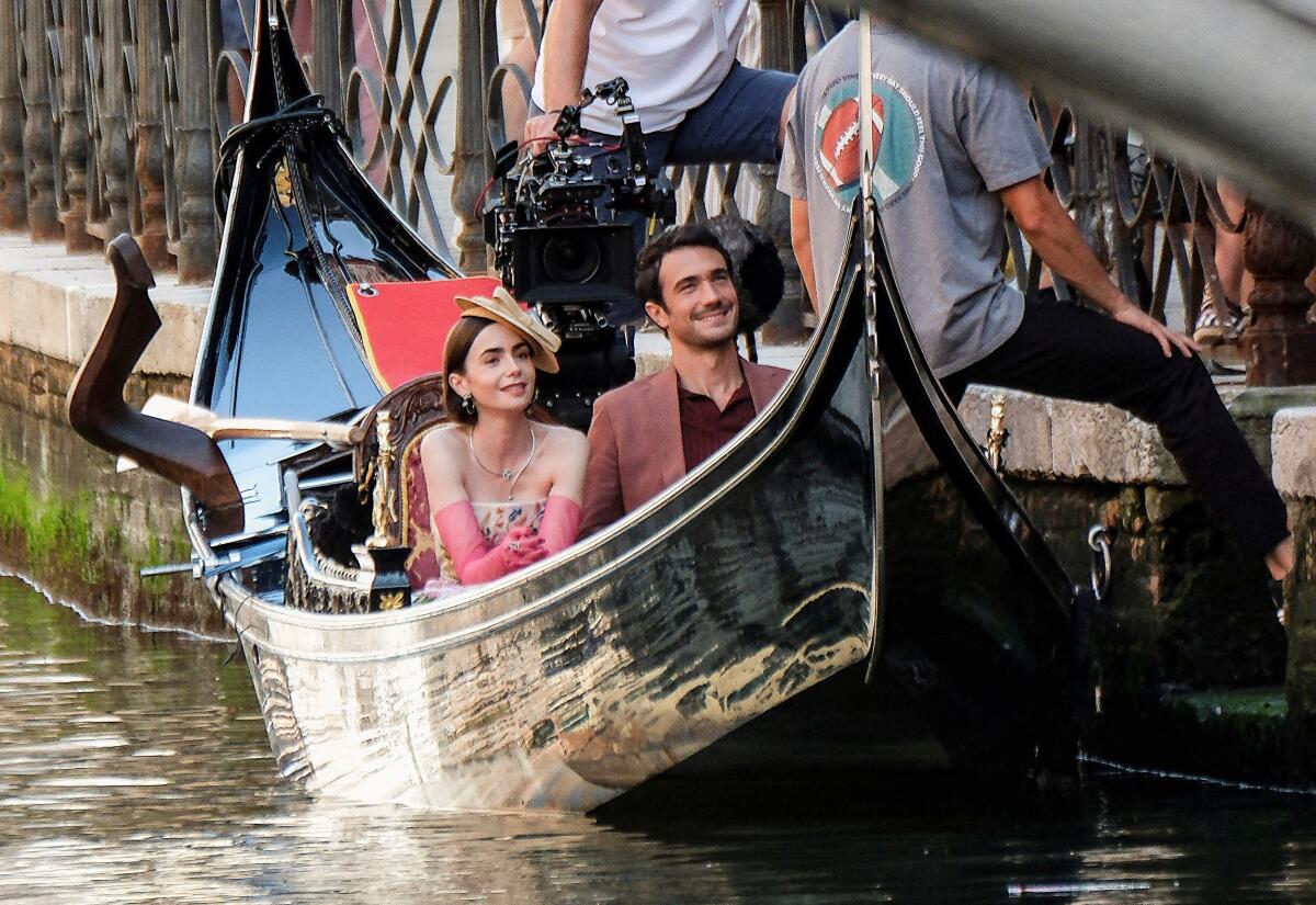 Actors Lily Collins and Eugenio Franceschini smile from a gondola during the production of Season 5 of Netflix's "Emily in Paris", in Venice, Italy August 23, 2025.