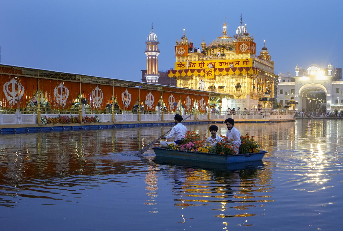 Volunteers carry flowers in a boat to decorate Golden Temple on the eve of the anniversary of the Sikh holy book Guru Granth Sahib's installation, also known as Guru Granth Sahib Parkash Utsav, in Amritsar, Saturday, Aug. 23, 2025.