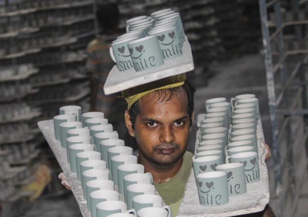 A worker carries ceramic cups at a pottery factory, at Khurja in Bulandshahr, Sunday, Aug. 24, 2025. India's pottery industry is expected to be affected by the recent hike in US tariffs on Indian exports.