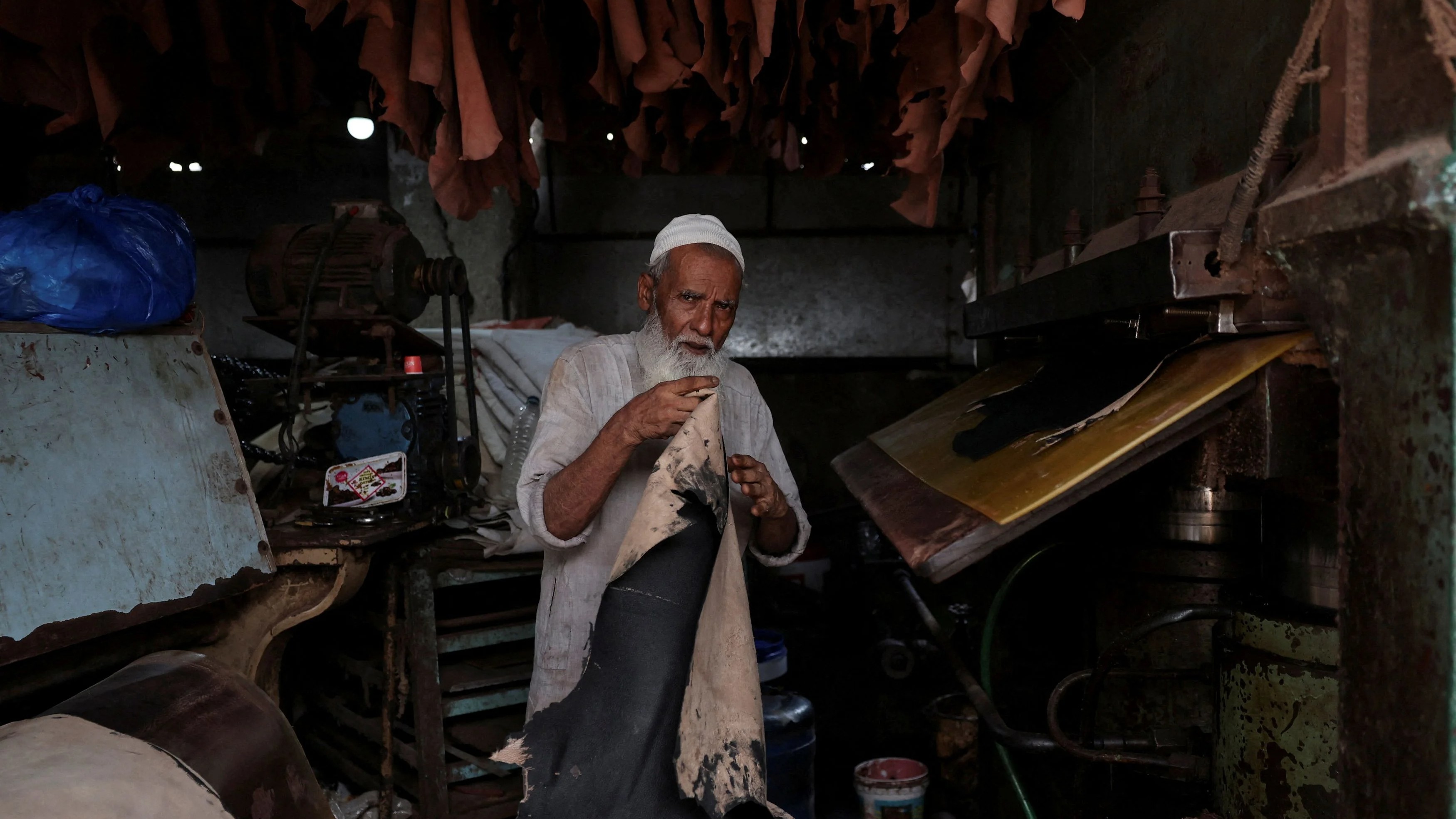 A man picks up coloured animal hide before putting it inside a press machine at a tannery in Mumbai.