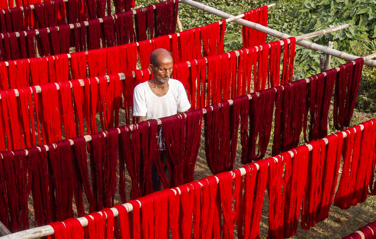 A worker puts dyed yarns for drying at a textile mill, on the outskirts of Agartala