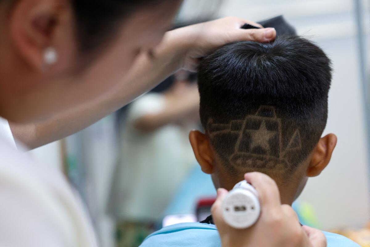 Hair salon owner Wang Xueru gives a child a haircut in a design of a tank to commemorate the 80th anniversary of the end of World War Two, at her store in Beijing, China