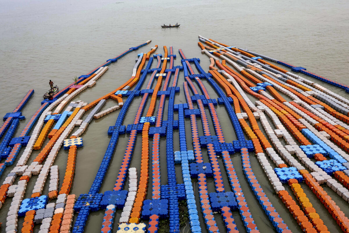 A man rows his boat past stranded floating jetties amid floods due to swollen Ganga river, in Prayagraj, Uttar Pradesh
