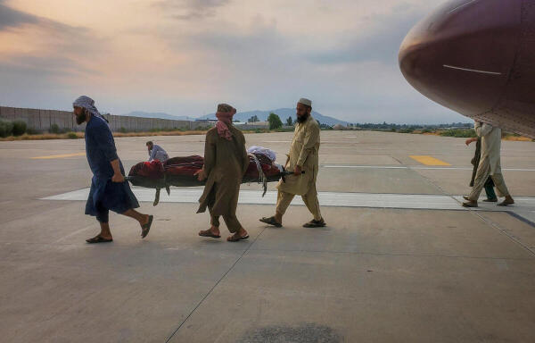 People carry an earthquake victim on a stretcher to an ambulance at an airport.