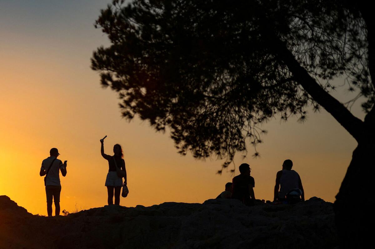 Locals and tourists enjoy sunset at Filopappou hill in Athens, Greece