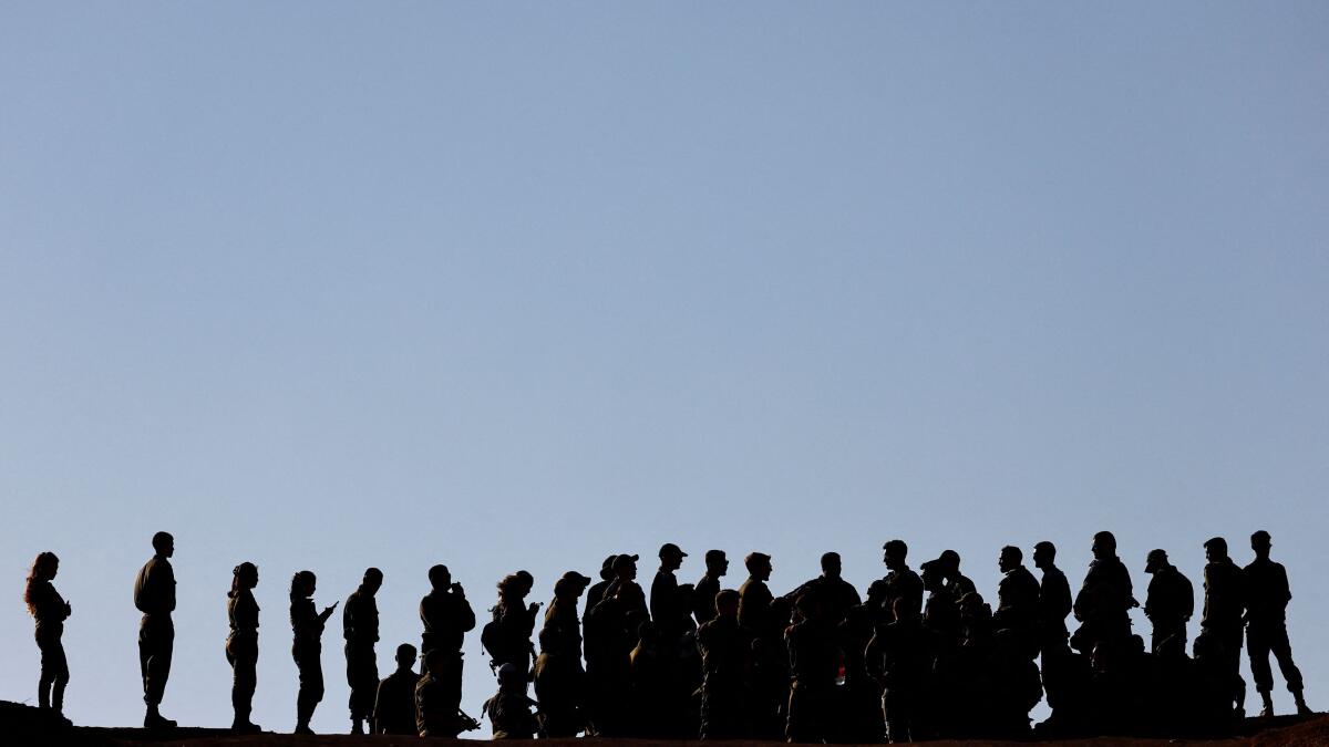 Israeli soldiers stand on the Israeli side of the border with Gaza