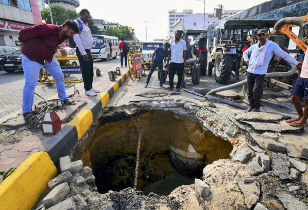 People stand near a caved-in portion of a road, in Jaipur.