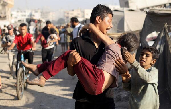 A Palestinian carries a wounded girl in the aftermath of an Israeli strike on the evacuated Al Jazeera Club, where displaced people had been sheltering, in Gaza City.