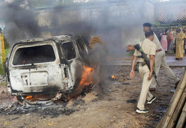 Police personnel try to douse a fire in a vehicle torched by people during an anti-encroachment drive by the district administration and Ranchi Municipal Corporation (RMC) in the alleged illegal slum areas, in Ranchi.
