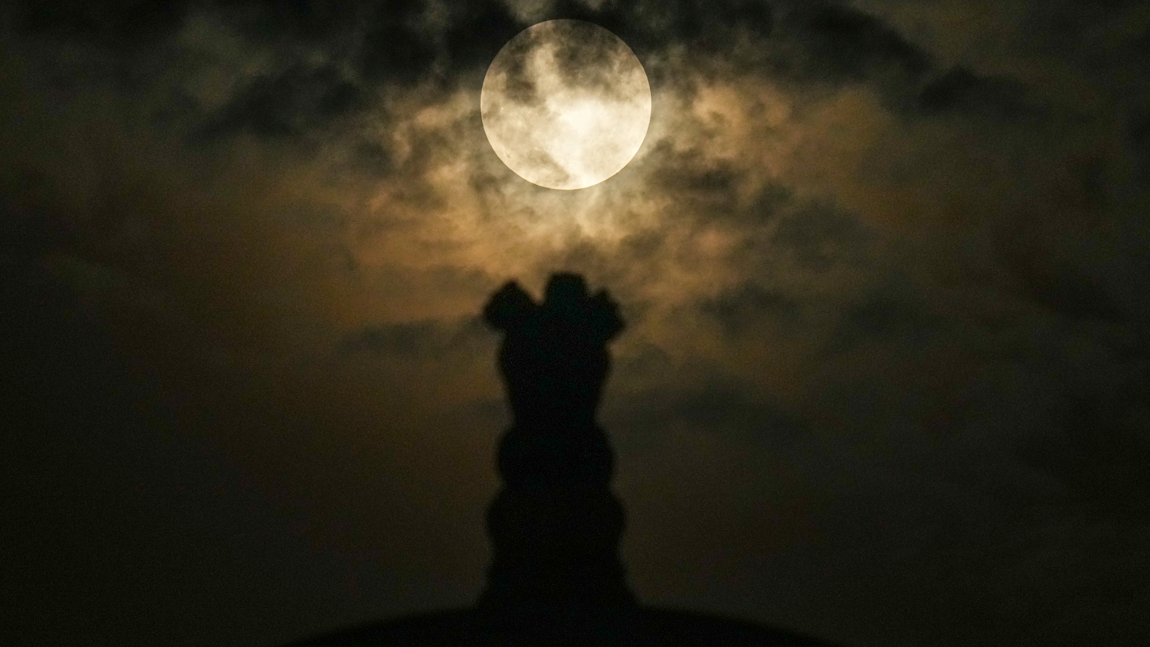 The moon rises behind ‘Ashok Stambh,’ or Pillar of Ashoka, ahead of the lunar eclipse in New Delhi.