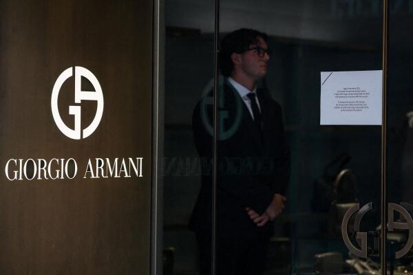 An employee stands near a door that has an announcement for closure of the shop for mourning on the day of the Italian fashion designer Giorgio Armani's funeral, at a Giorgio Armani store on Via dei Condotti, in Rome, Italy.