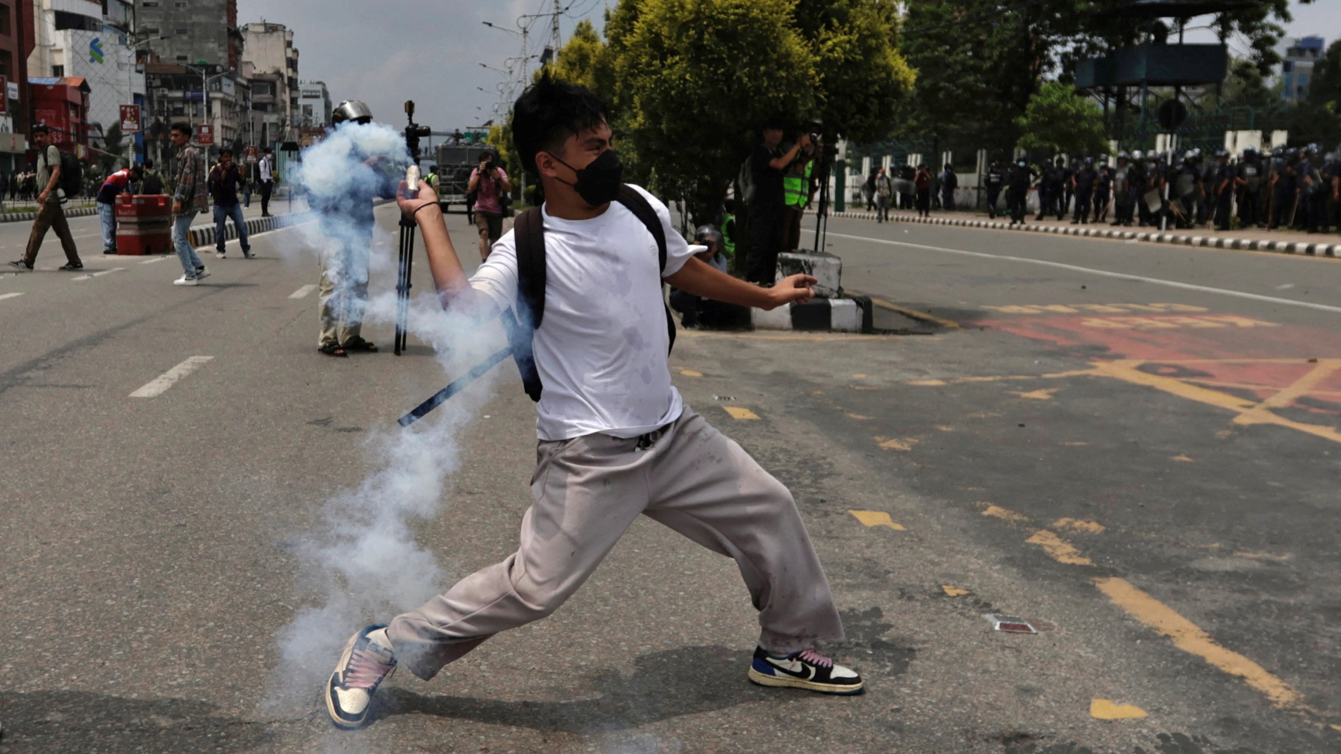 A demonstrator hurls a tear smoke shell towards members of riot police during a protest against corruption and the government’s decision to block several social media platforms in Kathmandu.