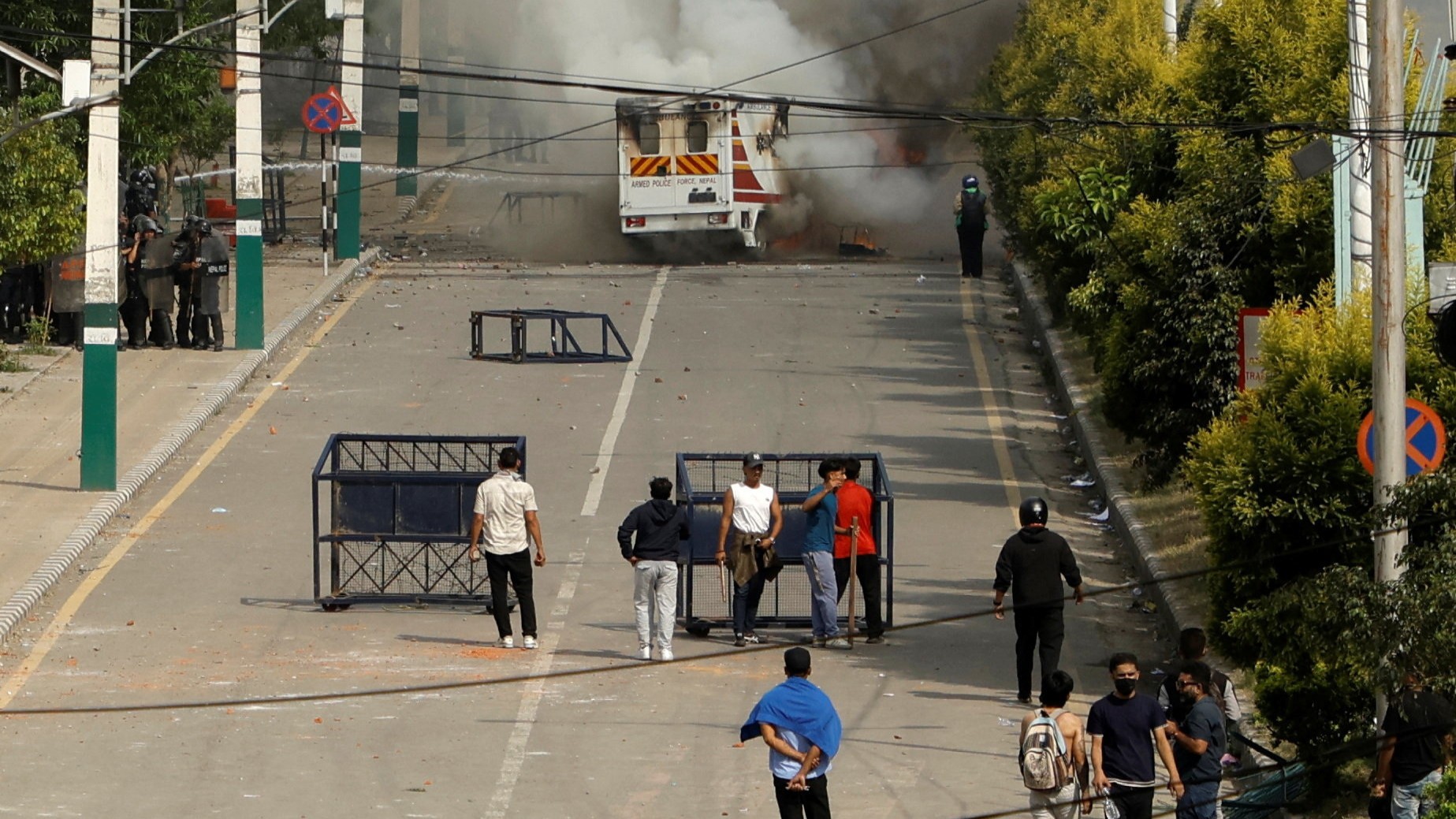 Smoke billows from an ambulance next to riot police officers and demonstrators during a protest against corruption and the government’s decision to block several social media platforms in Kathmandu.