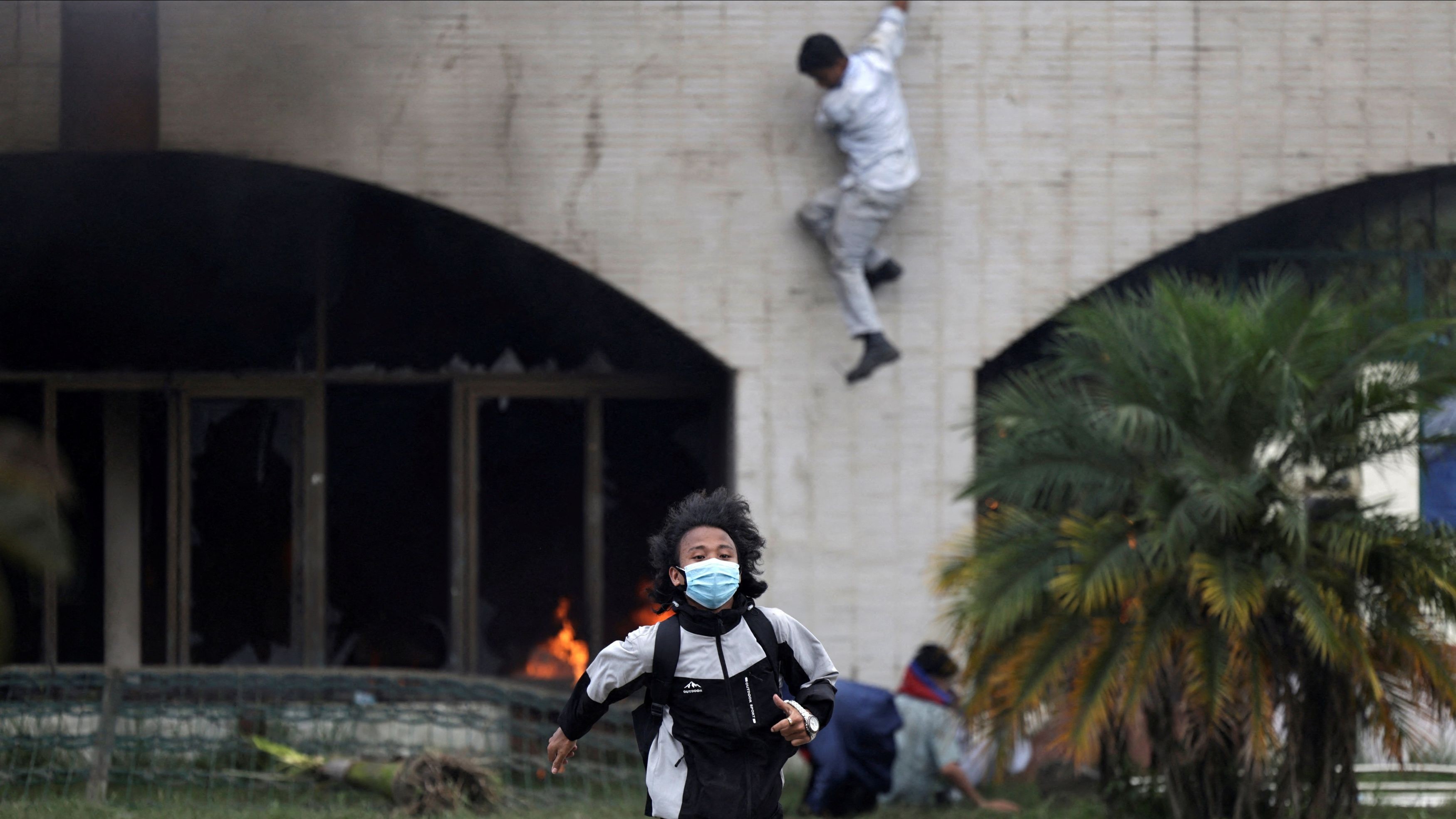 A demonstrators runs for cover as they are chased away by police jumps during a protest against corruption and the government’s decision to block several social media platforms, in Kathmandu.