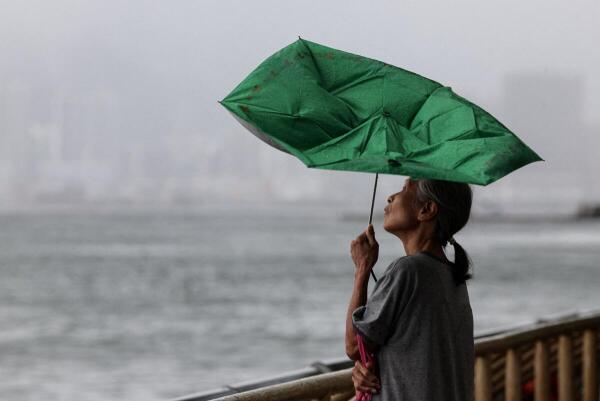 A woman holds an umbrella inverted by winds as Tropical Storm Tapah approaches in Hong Kong, China.