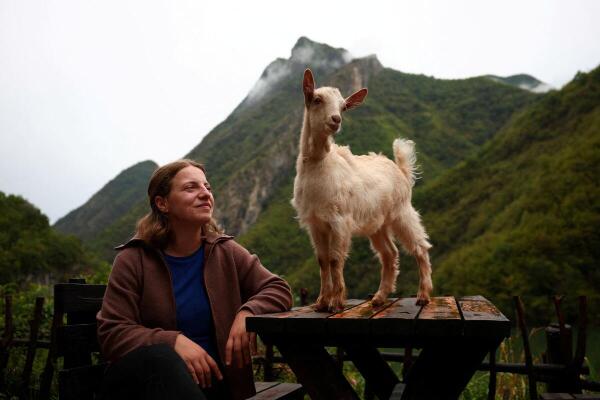 Marjana Koceku (24), newly elected MP, and her goat look on at her stone house transformed into an agritourism guesthouse in a remote area at Koman lake near Shkodra, Albania.