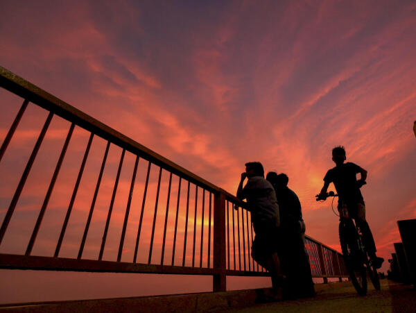 A boy rides a bicycle on a bridge over River Ganga during sunset, in Prayagraj.