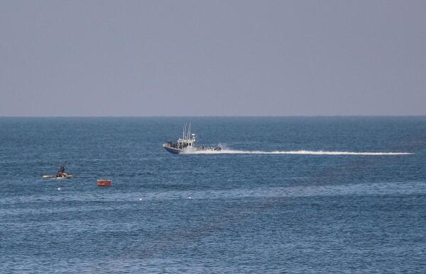 An Israeli navy boat sails near Palestinian fishermen off the coast of the central Gaza Strip.