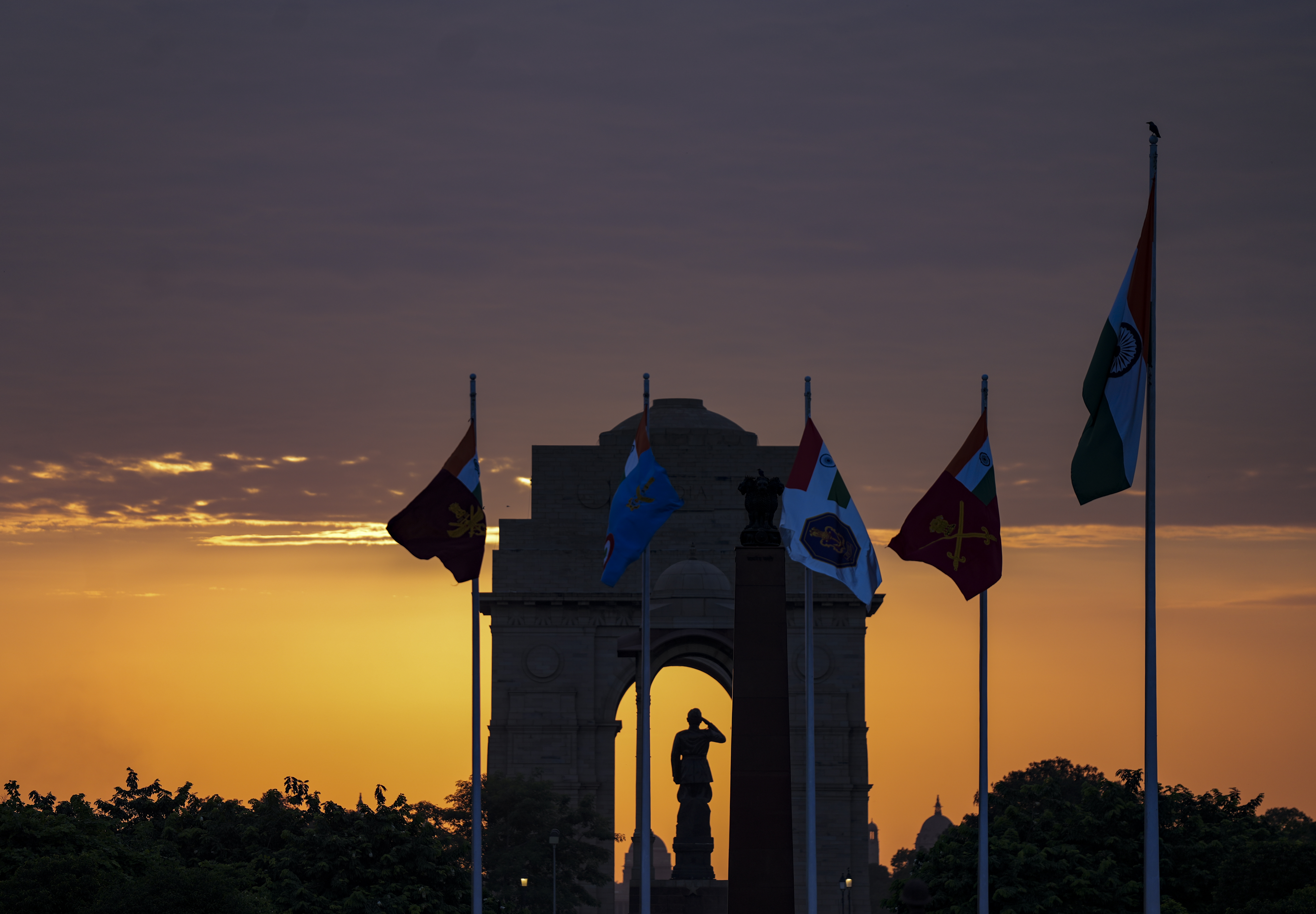 The Indian national flag along with flags of the Integrated Defence Staff, Army, Navy and Air Force waves as the sun sets behind the India Gate