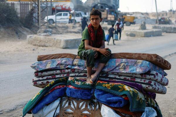 A displaced Palestinian boy, fleeing northern Gaza due to an Israeli military operation, sits atop belongings as he moves southward after Israeli forces ordered residents of Gaza City to evacuate to the south, in the central Gaza Strip.