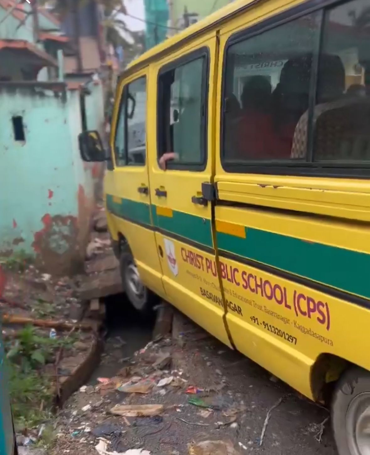 The Christ Public School bus had its front wheel trapped in an open drain on a narrow road. The driver struggled to free the vehicle. DH PHOTO