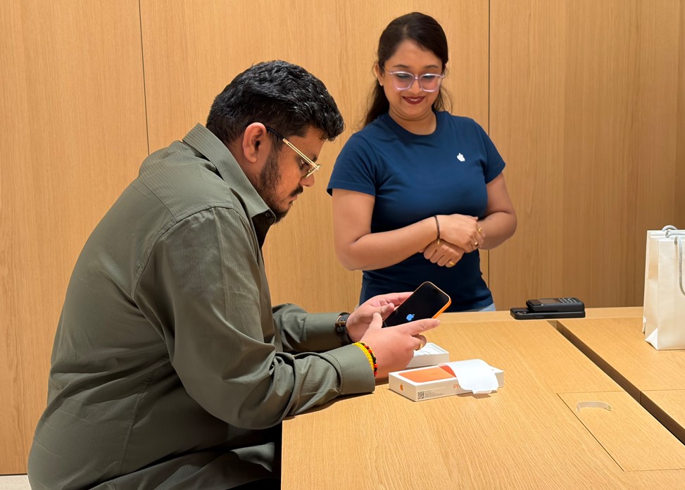 Customer setting up his iPhone 17 Pro Max Cosmic Orange model at Apple Hebbal Store.