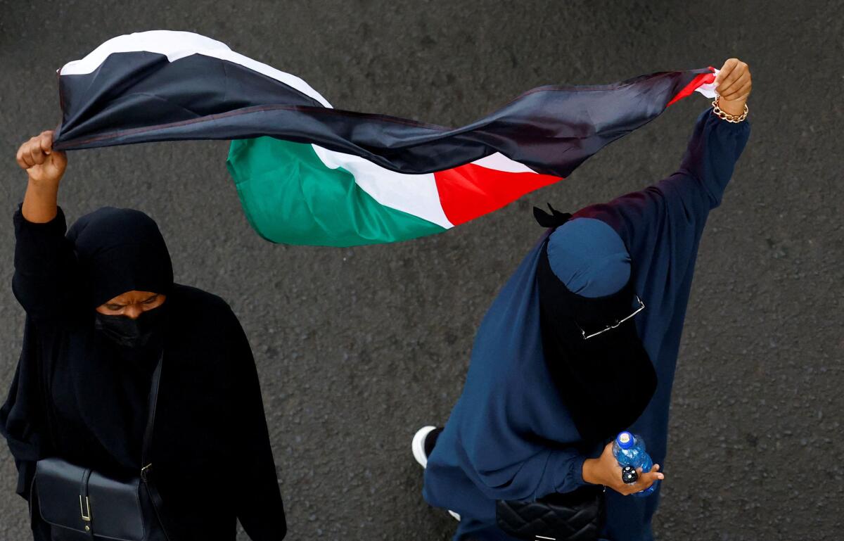 Women hold a Palestinian flag as they participate in a "Free Palestine" protest in support of Palestinians, in Nairobi, Kenya.