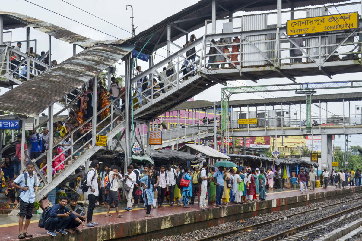 Passengers wait at a platform after train services were disrupted due to rainfall, in South 24 Parganas.