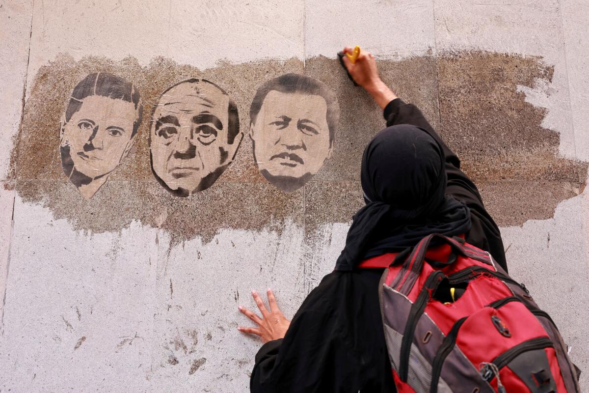 A demonstrator pastes images of Mexico's former President Enrique Pena Nieto, former Attorney General Jesus Murillo Karam and former Governor of Guerrero Angel Aguirre on a wall, as relatives and friends of the 43 students from Ayotzinapa who disappeared in 2014 gather to mark the anniversary of the students' disappearance, in Mexico City, Mexico.