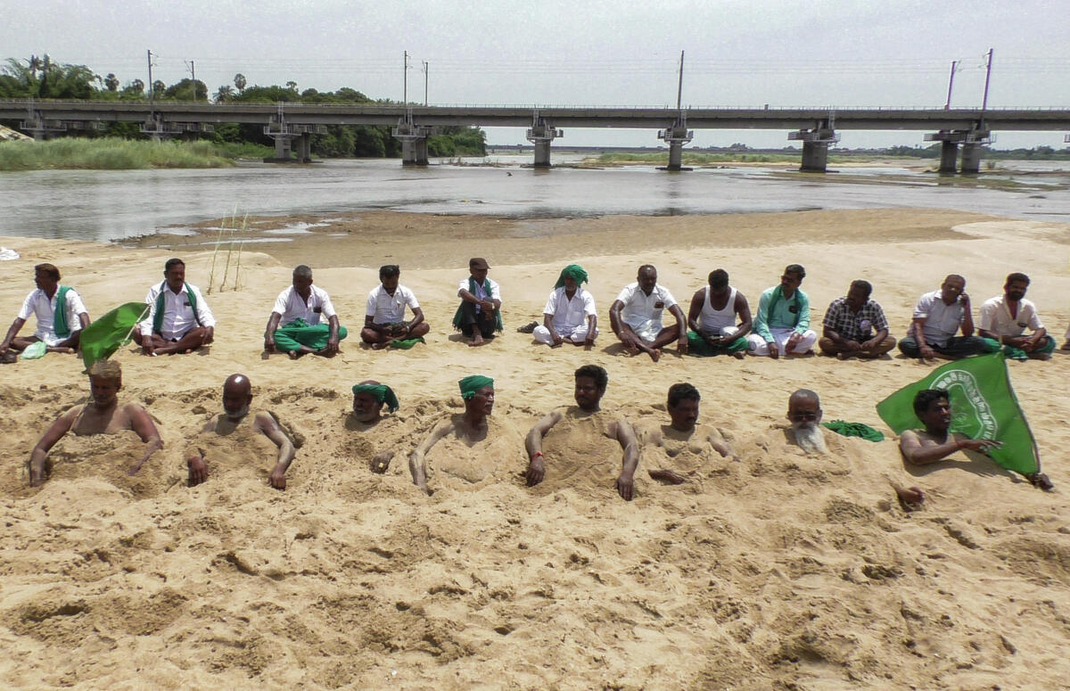 Farmers, led by Ponnusamy Ayyakannu, chief of the Desiya Thenidhiya Nathigal Inaippu Vivasayigal Sangam, stage a protest by burying themselves in sand near the Cauvery River, with demands related to water sharing and agricultural support systems, in Tiruchirappalli, Tamil Nadu.