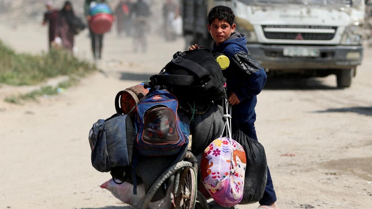 A boy stands with his belongings as Palestinians make their way to flee their homes, after the Israeli army issued evacuation orders for a number of neighbourhoods, following heavy Israeli strikes in the northern Gaza Strip.