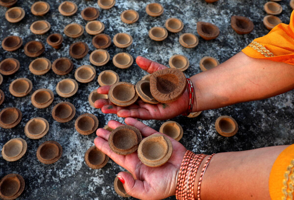A woman shows ‘diyas’, earthen lamps, made of cow dung amid preparations for the upcoming ‘Diwali’ festival
