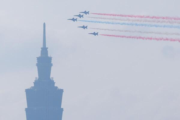 AT-3 advanced jet trainers release colored trails as they fly in formation past Taipei 101 during a Taiwan's National Day rehearsal.