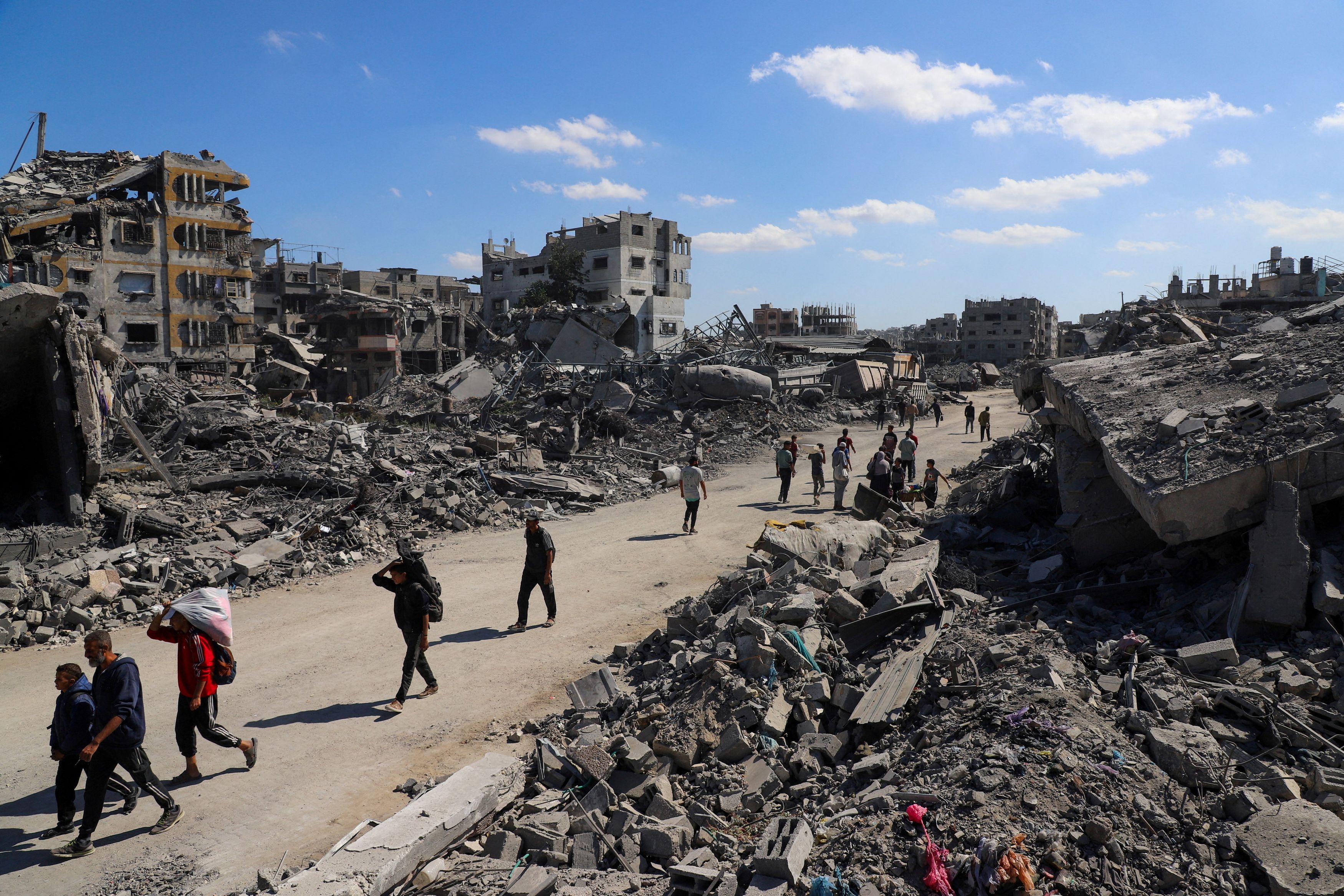Palestinians walk past the rubble of destroyed buildings, amid a ceasefire between Israel and Hamas, in Gaza City