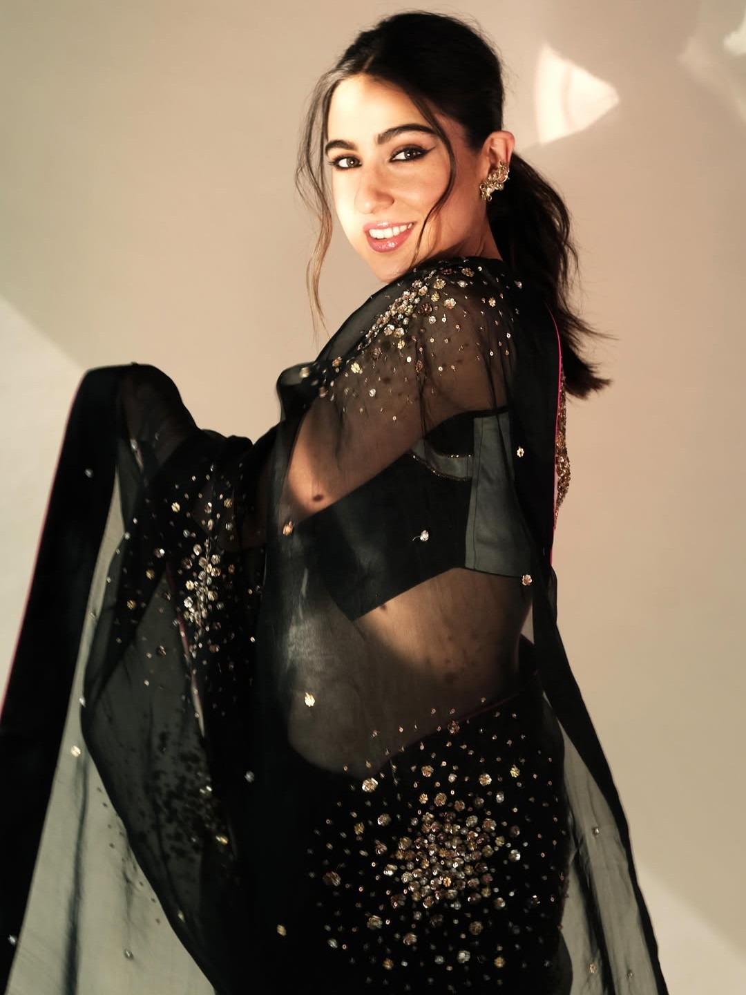 For a striking Diwali look, channel Sara’s style in a black georgette saree. Featuring intricate golden details, a V-neck blouse, a sleek ponytail, and understated makeup, this ensemble blends timeless elegance with festive charm.