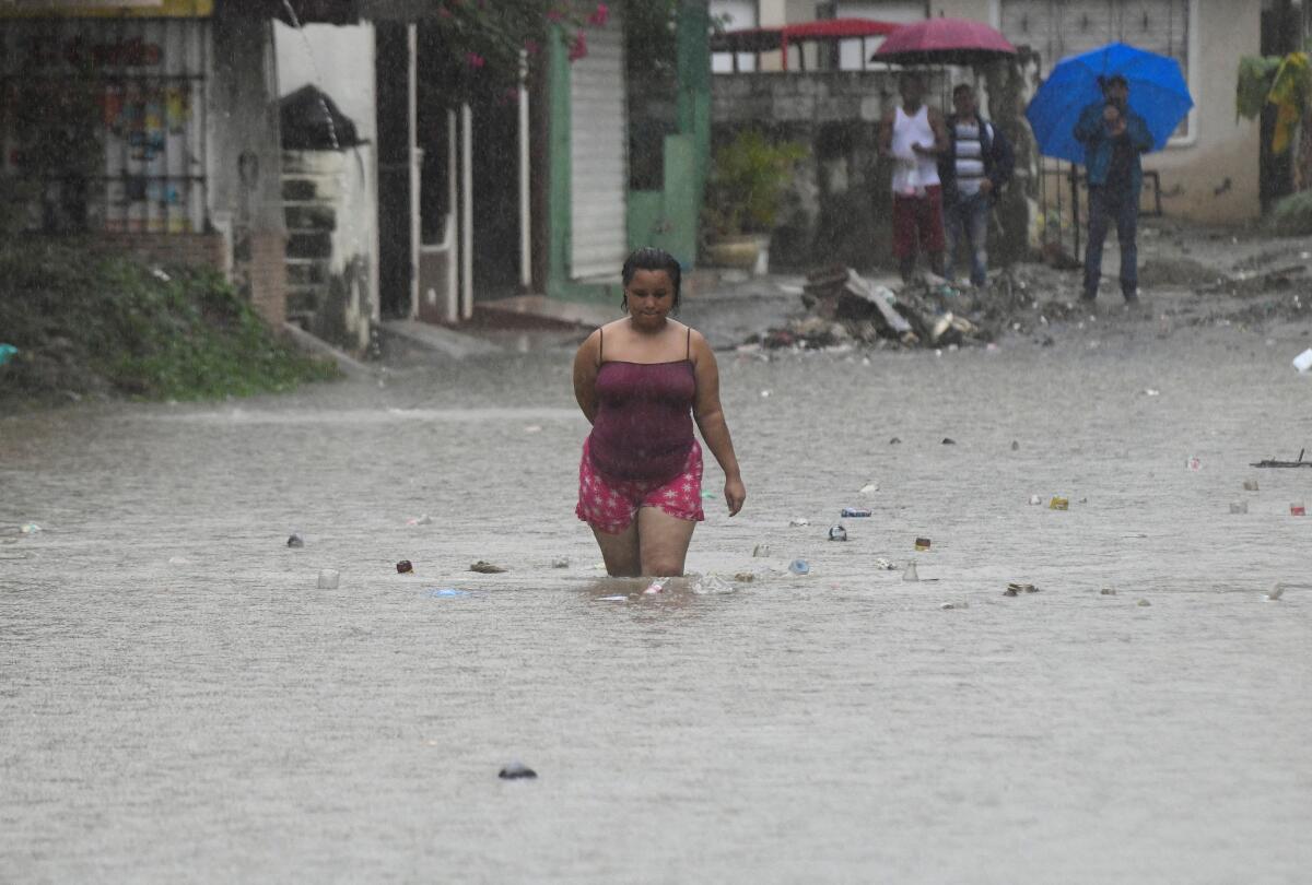 A woman walks along a flooded street amid rain caused by Tropical Storm Melissa, in Santo Domingo, Dominican Republic.