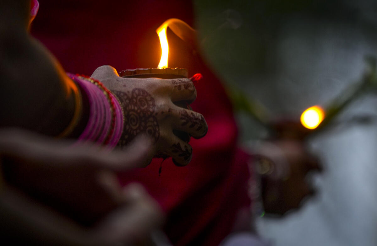 A woman offers prayers to the setting sun at the bank of River Hindon as part of Chhath Puja festival rituals, in Ghaziabad